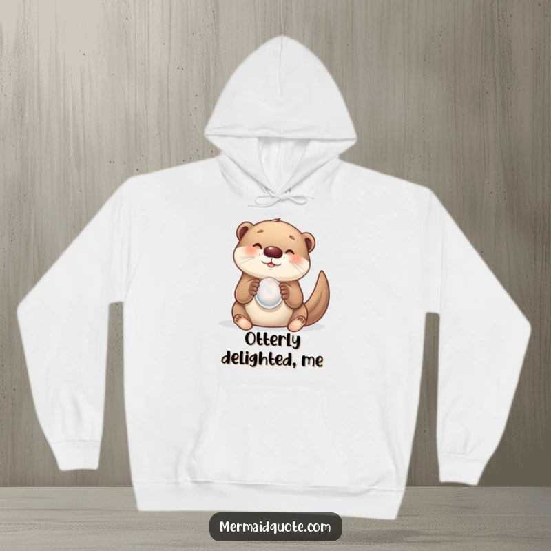 Funny, warm hoodie showing a curious otter creature overjoyed with a luminous pearl. A delightful and cozy design.