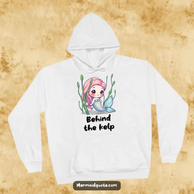 Funny hoodie depicting a curious mermaid with shimmering scales, peeking from behind seaweed, offering warmth and underwater charm.